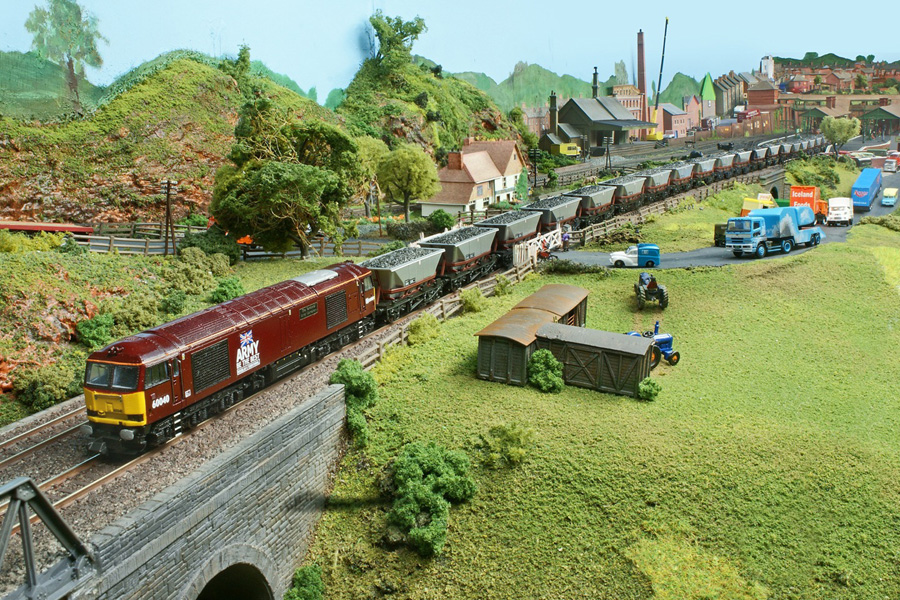 No 60 040 'The Territorial Army Centenary' holds up the traffic with a long train of HAA hoppers. Behind the Co-op Morris van is a simulator ride for funfairs, by Simon Addelsee.