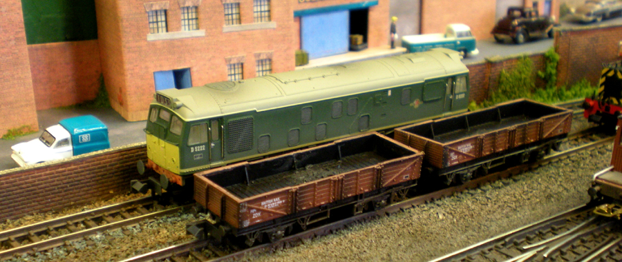 A grubby green Class 25 waits while the 04 (just visible on the far right) shunts a few empties.